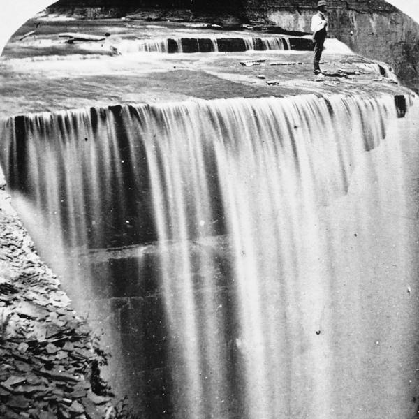 Man standing at the lip of Taughannock Falls in the 1800s