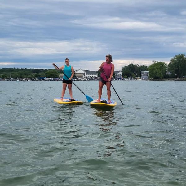 Two women learn how to paddleboard on Canandaigua Lake