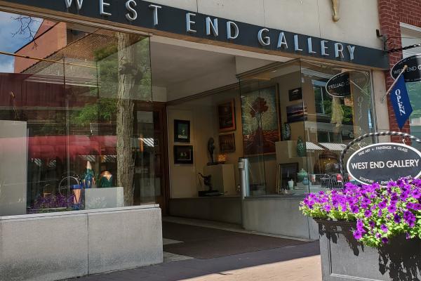 front exterior of gallery with black background of sign and white 'West End Gallery' text on front top of building entrance 