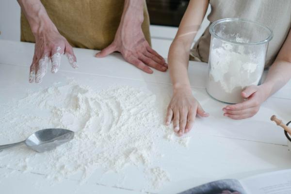 Two sets of hands scooping flour