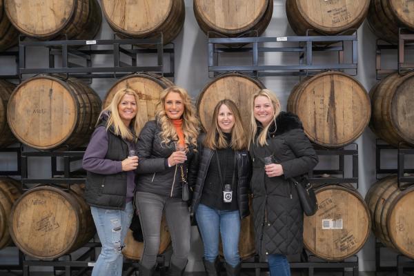 Four Prison City's Fire and Ice Festival attendees pose in front of bourbon barrels inside the brewery.