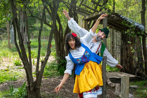 Actors portraying Snow White and Dwarf Four cross a small wooden bridge with their arms raised