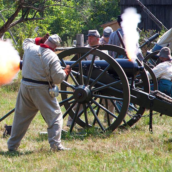 cannon blasting on battlefield with actors in soldier costumes attending to cannon