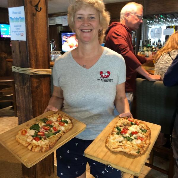 Mary Alice, owner of Beachcomber restaurant, holding 2 flatbread pizzas 