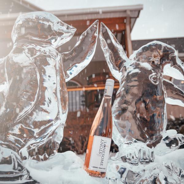 Frost Fest February 15th 2020 at Three Brothers Wineries. Photo of two penguins carved out of ice high fiving with a bottle of wine between them