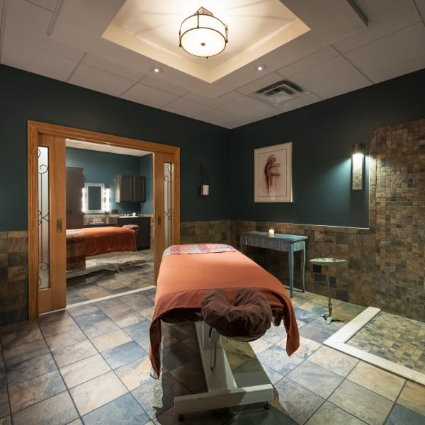 spa room with overhead light and spa massage table in center of room with pink blanket covering table