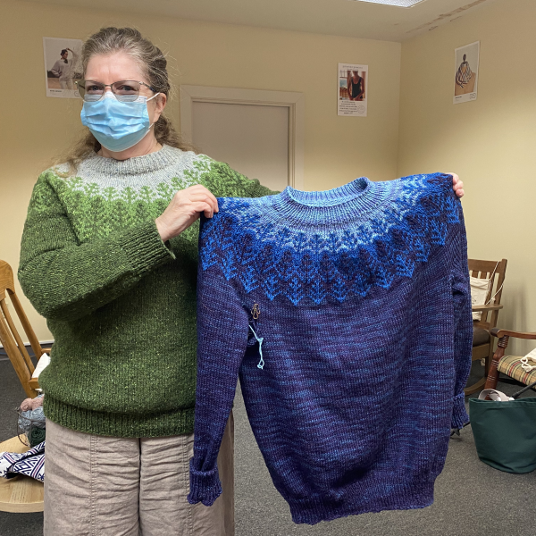 knitter showing off her finished forest sweaters