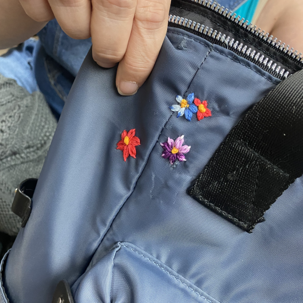 visible mending - embroidered flowers on a torn backpack