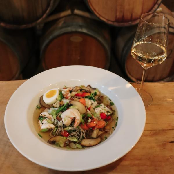 Shrimp ramen bowl next to a glass of white wine.