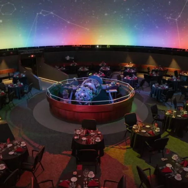 The Star Theater at RMSC Strasenburgh Planetarium with round tables set up. On the tables are full service and flowers.