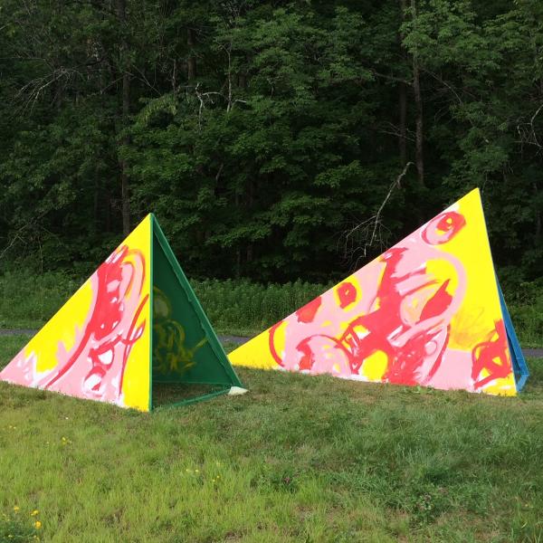 Two painted geometric forms sitting in green grass.