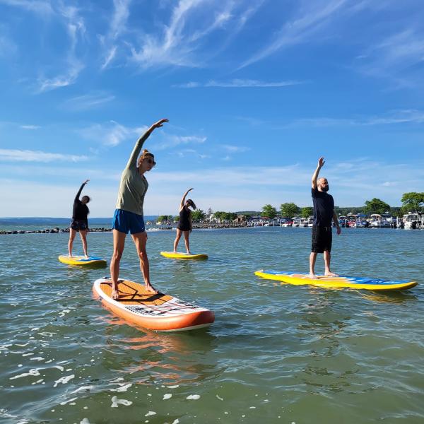 Paddleboard yoga class does crescent side stretch