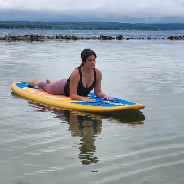 Woman does sphinx pose on paddleboard