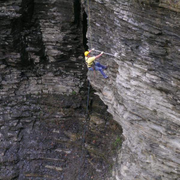 A scaler pries loose rock from a high cliff in Watkins Glen State Park, Watkins Glen, NY.